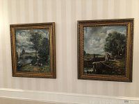 Both framed paintings hanging on striped wallpaper wall