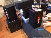 Multiple Kenwood surround sound speakers stacked with stereo components visible below.