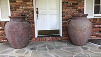 Overview of both urns placed side by side on stone porch in front of door