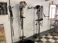 Wall-mounted Stihl trimmer, tiller and chains hanging on pegboard