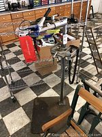 Full view of repair stand with clamp head, base plate and chainsaw chain draped over tray