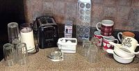 Countertop with all kitchen items arranged including glassware, coffee mugs, appliances, and accessories.