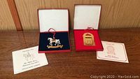 Both Christmas ornaments in their original presentation boxes with accompanying informational pamphlets.