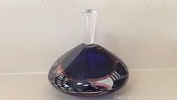 Perfume bottle front view showing deep blue glass and clear stopper.
