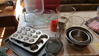 Overview of baking pans, mixing bowls, hand mixer, strainer on table