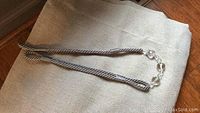 Photo of the crystal jewel rope tie backs showing the clear faceted beads and twisted gray and white rope detail on top of folded light gray gauze fabric.