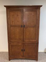 Front view of closed Mission style oak entertainment cabinet showing four doors and metal latch hardware.