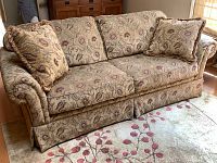 Full view of Broyhill tapestry sofa with three matching fringed pillows on a patterned area rug.