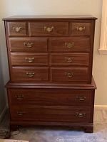 Front view of wooden highboy dresser showing upper and lower drawers with colonial brass pulls.
