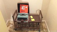 Full view of the vintage TV cart holding the portable typewriter and Eaton typewriter paper box on top.