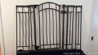 Full view of bronze metal safety gate with two extension panels and mounting hardware.