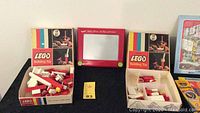 Overview of two LEGO Building Toy sets with red and white bricks and red Etch A Sketch toy in center