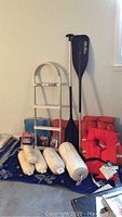 Overview of boating items showing life preservers, ladder, oars, and bumpers arranged on floor
