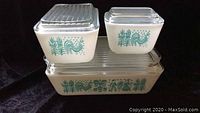 Three vintage Pyrex Butterprint refrigerator containers displayed with lids, showing the Butterprint roosters and corn stalk pattern.