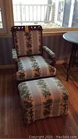 Carved wooden framed upholstered chair with floral striped fabric and matching ottoman