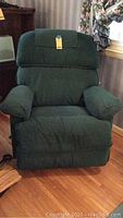 Front view of dark green fabric La Z Boy rocker recliner with padded arms and cushioned backrest.