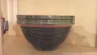 Side view of green glazed vintage ceramic bowl with decorative patterns under rim and wave groove details.