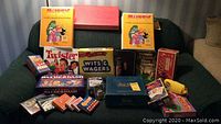 Full view of the games laid out on a green upholstered couch showing all game boxes and some card decks.