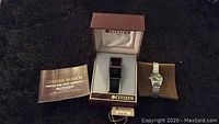 Citizen Quartz Watch in original brown box with warranty booklet, and second silver tone stretch band watch on brown cushion.