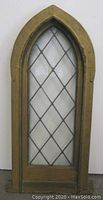 Front view of the Gothic arch leaded glass church nave window showing clear diamond pattern glass panes and wooden frame.
