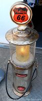 Photo of lamp top showing Phillips 66 round logo with metal mesh surrounding light bulb