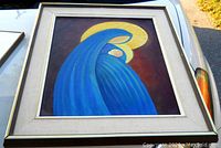 Full view of framed abstract Madonna and Child painting showing blue figure with yellow halo on dark background.