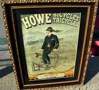 Frontal close-up of the framed Howe Bicycles and Tricycles advertising poster showing the figure on the tricycle and text clearly.