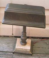 Front view of bronze Art Deco banker’s lamp on cream marble base showing pull chain and original cord