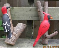 Both wood-carved birds with natural wood branch mounts, showing front view and scale