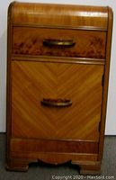 Front view of the nightstand showing the burled wood drawer and cabinet door with twin bakelite handles.
