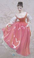 Full frontal view of the 'Fair Lady' porcelain figurine showing her coral pink dress and detailed puffed sleeves.