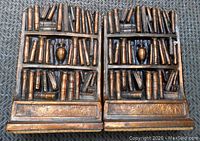 Front view of the bronzed metal library bookends showing detailed books and central urn on shelves