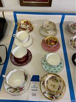 Full view of all 8 tea cups and matching saucers showing variety of floral designs and gold trim.