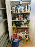 Front view of white metal cabinet filled with garden chemicals and tools