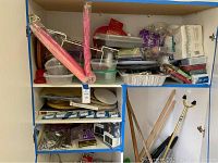 Shelves with assorted plastic food storage containers, covered baking tin, aluminum pans, napkins, wooden nut crackers, umbrella food covers, and serving trays.