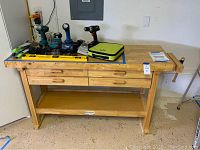 Full view of the wooden workbench with various tools on top (tools not included). Shows the 4 drawers and lower shelf.