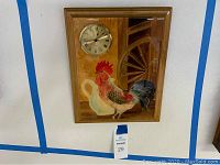 Front full view of hand made wall clock featuring a rooster and wood water wheel design with clock mounted on the top left.