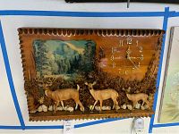 Front view of handcrafted wooden clock featuring three deer and natural woodland scene with mountain background.