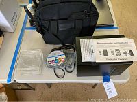 Wide view of all items included: DVD duplicator, spindle of CD-R disks, cables, clear DVD cases, black canvas tote bag, easy start guide.