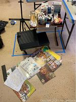 Overview of easel, folding drawing table, small side table with craft paints, brushes and art books spread on floor