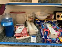 Full view of all items on kitchen counter including Presto Air Popper in blue and FoodSaver sealer with various boxes of plastic wrap and foil