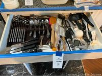 Drawer with stainless steel flatware including spoons, forks, knives, cooking utensils, digital meat thermometers, and steak knives
