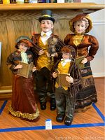 All four Victorian caroler figurines grouped in front of wooden ledge