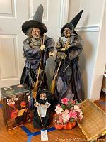 Two tall witches made with umbrella base, one rocking witch figure in original box, pumpkin dish with floral arrangement, and basket visible