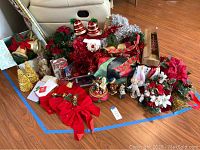 Wide view of assorted Christmas decorations on floor including bows, figurines, garlands, and wreaths.