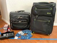 Photo showing IFly suitcase, laptop case, neck warmer, travel valet kit, Travelese wrist bands, and playing cards arranged on floor.