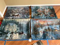 Overview of all four fiber optic tapestry wall hangings laid out on floor showing different winter and Christmas scenes.