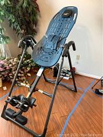 Full front view of blue Teeter Hang Ups inversion table on black frame with ankle support