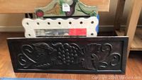 Dark stained wooden decorative wall art with grape leaves and grape cluster in relief, photographed from different angles