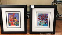 Two framed colorful art prints by A.E. Barnes displayed together, showing the lot includes a pair of artworks with black frames.
